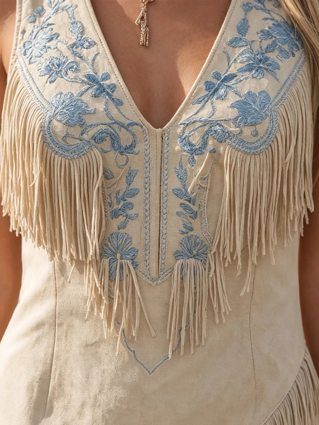 Western-Style Mini Dress — Beach Beige With Heavy-Duty Sky Blue Floral Embroidery, Tasseled Front, And Asymmetrical Cut.